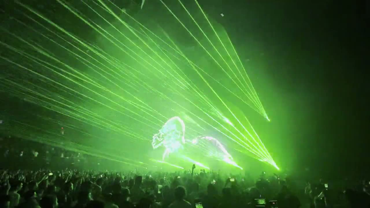 Green laser beams fanning out over a concert crowd