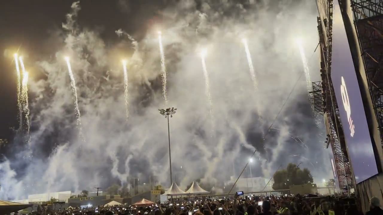Pyrotechnic cascades fired over a packed stadium at a night event
