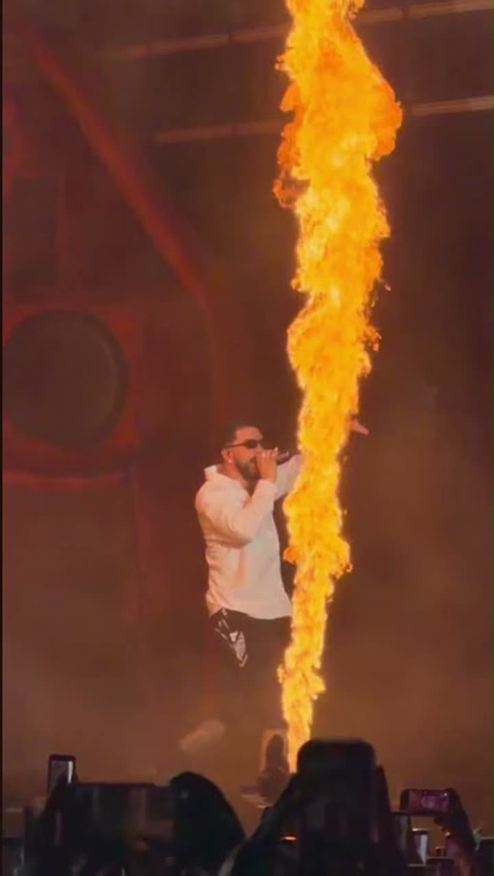 Columna de llama disparada desde el escenario mientras el artista canta frente al público del festival