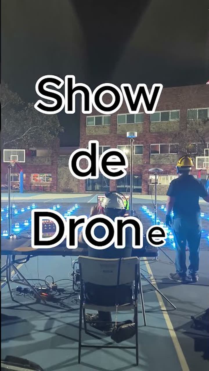 Parrilla de despegue con drones encendidos en una cancha, con la consola de control y la cuadrilla con casco
