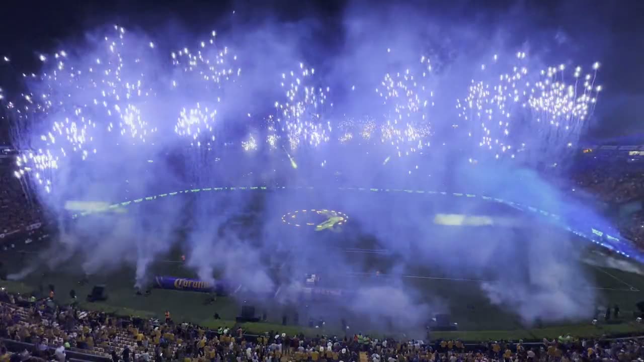 Aerial view of a packed stadium with gold and blue pyrotechnics fired from the pitch