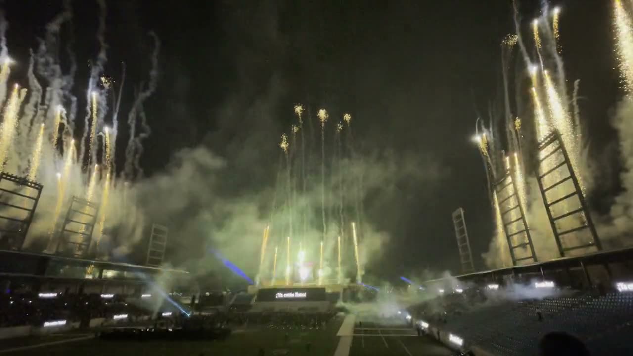 A wall of pyrotechnic cascades and laser beams over a university campus at night